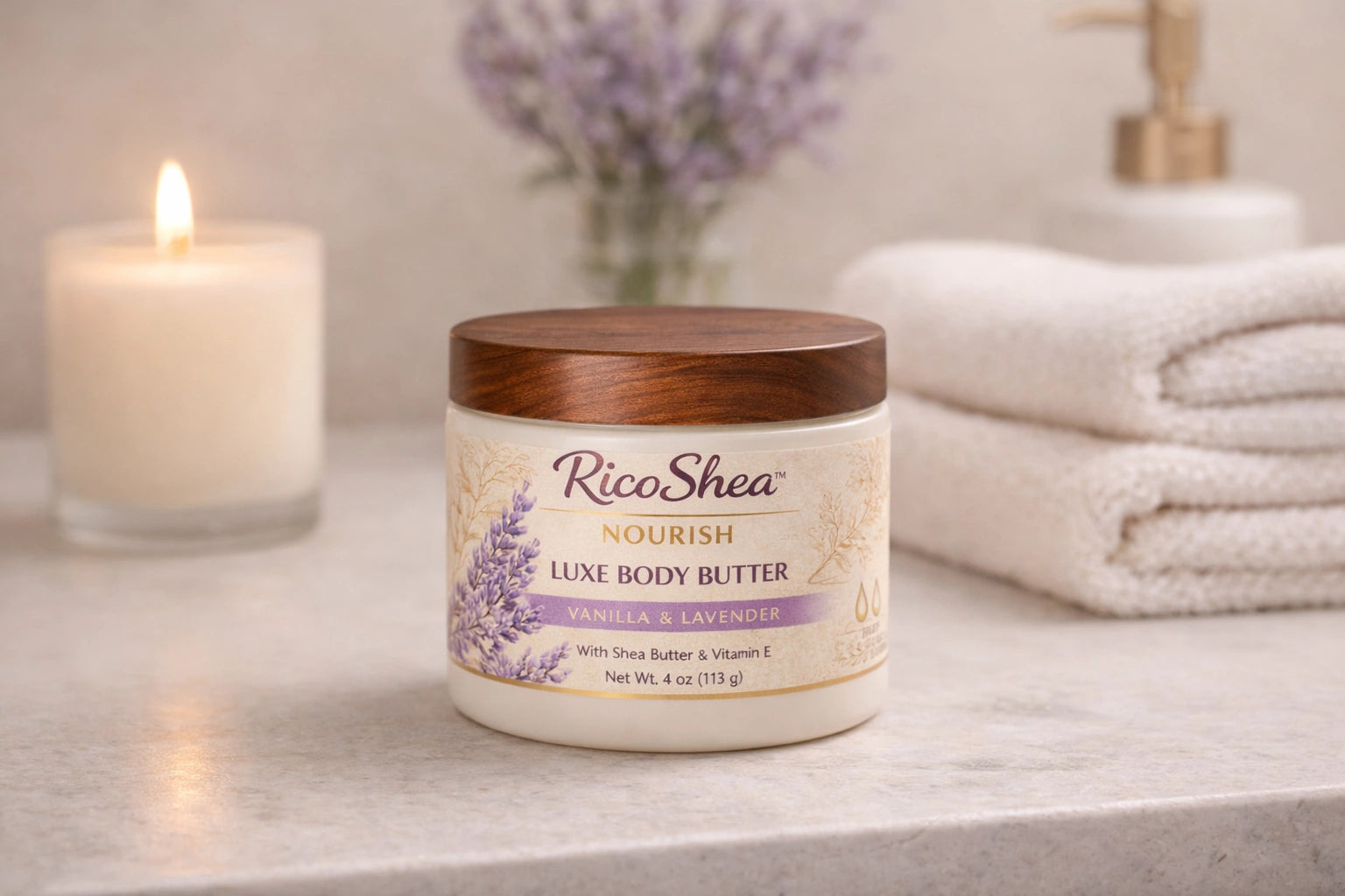 RicoShea Luxe Body Butter jar with lavender label on a bathroom counter with a candle and towels in the background.